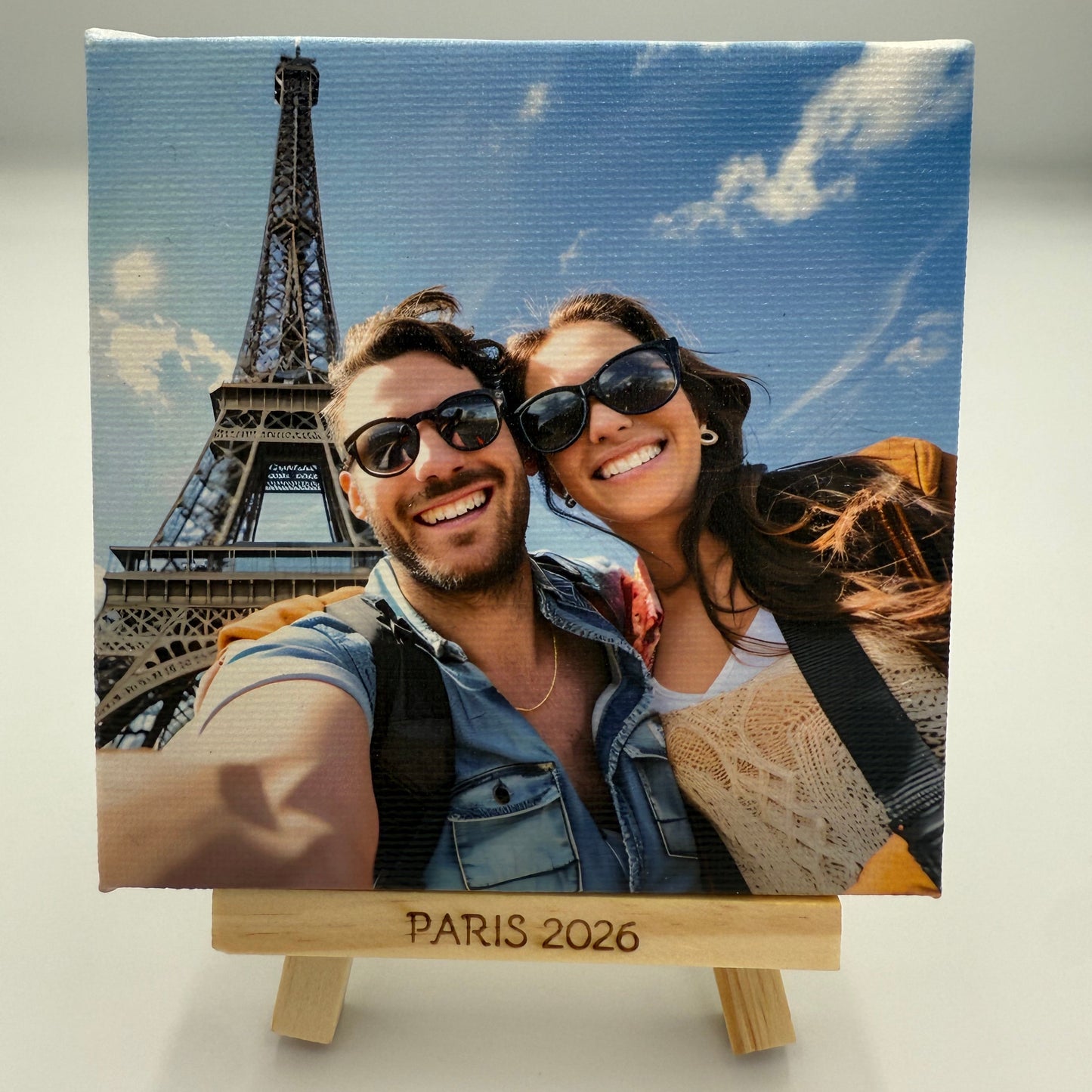 Canvas print of a couple in front of the Eiffel Tower with 'Paris 2026' text.
