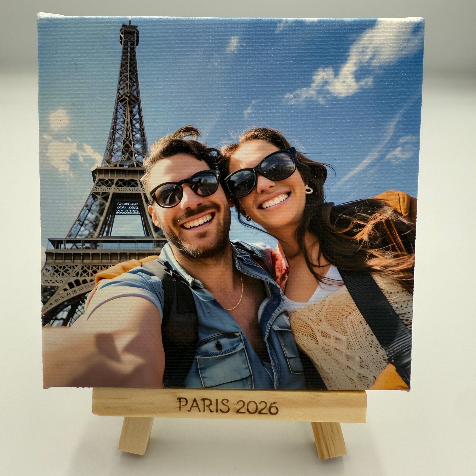 Canvas print of a couple in front of the Eiffel Tower with 'Paris 2026' text.